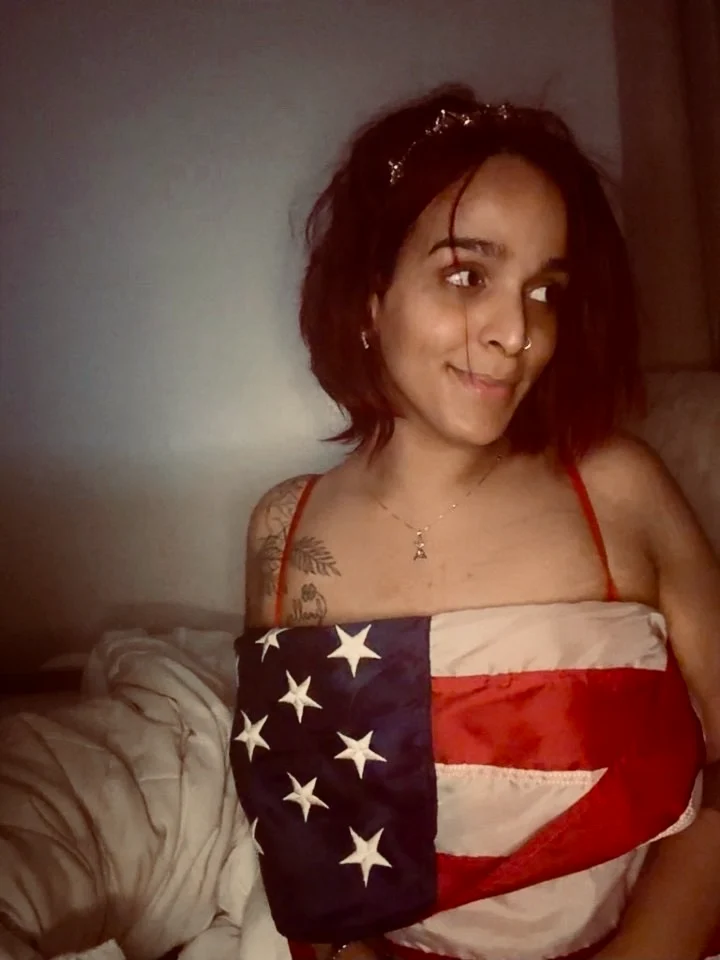Ava wrapped in an American flag, smiling and looking away